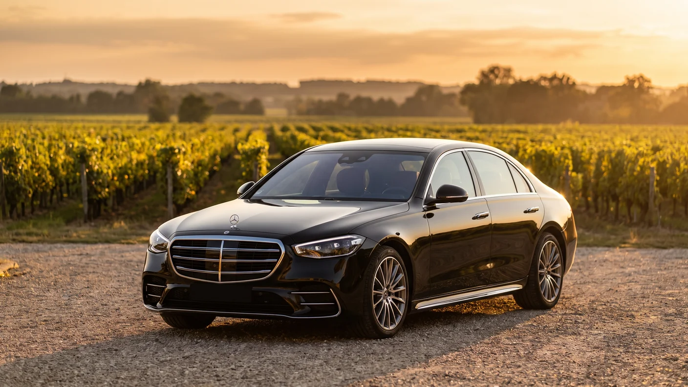 VTC de luxe à Bordeaux : berline de prestige Mercedes Classe S noire avec chauffeur devant un château du vignoble bordelais