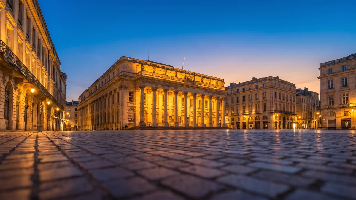 Berline de prestige avec chauffeur devant le Grand Théâtre place de la Comédie à Bordeaux la nuit